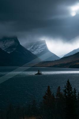A green-toned moody photograph of lakeside, valley, boathouse.