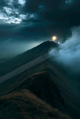 A night long exposure landscape of mountains, sunrise, moon.