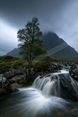 A serene long exposure water scene of waterfall, river, trees.