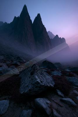 A black-toned moody photograph of alp, valley, mountain tent.