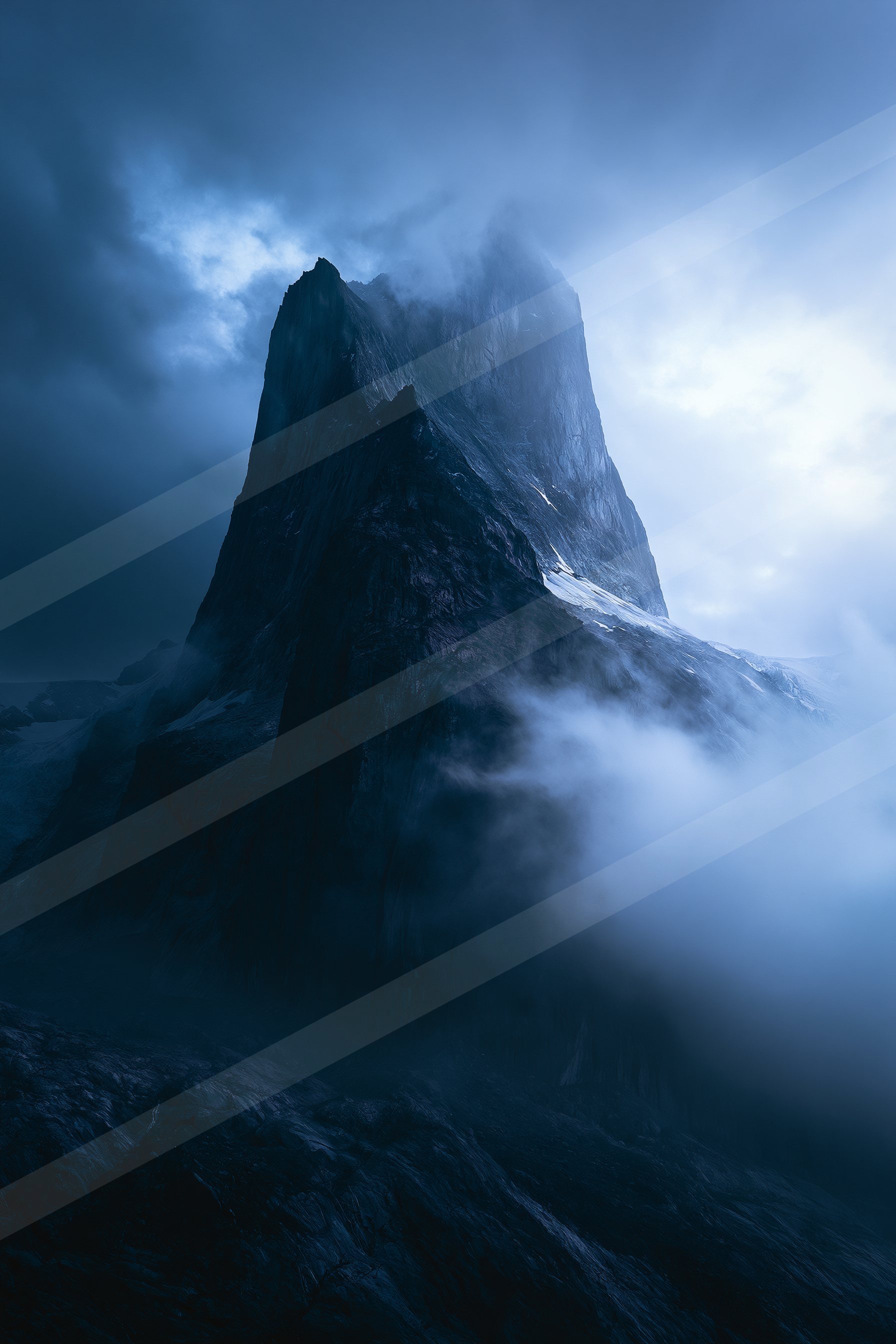 A towering mountain peak shrouded in misty clouds under a moody sky.