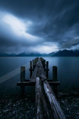 A black-toned moody photograph of breakwater, pier, dock.
