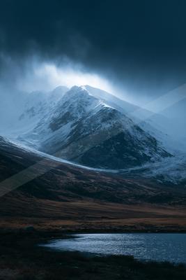 A moody high contrast landscape of a mountains, snow.