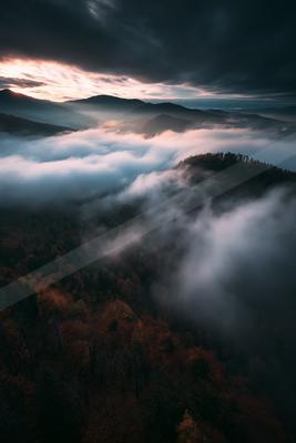 A moody landscape of mountains, valley, clouds.