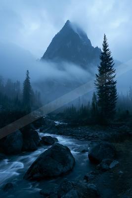 A blue hour long exposure landscape of mountains, river, fog.