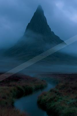 A sharp rocky mountain peak rises through thick blue mist above a winding stream flowing through reddish-brown moorland vegetation.