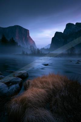A blue hour long exposure landscape of mountains, valley, river.