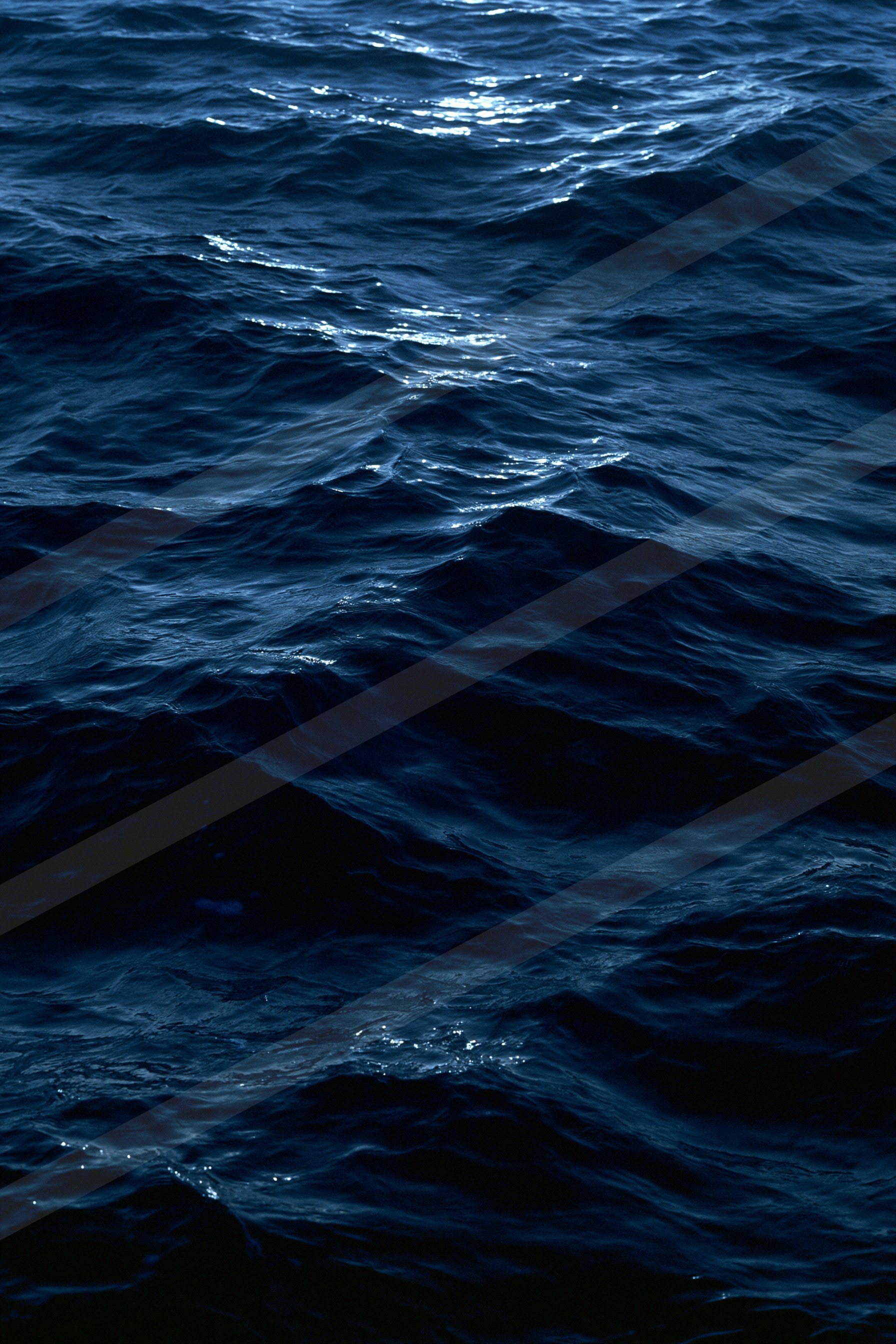 A serene view of deep blue ocean waves rippling gently under low light conditions.