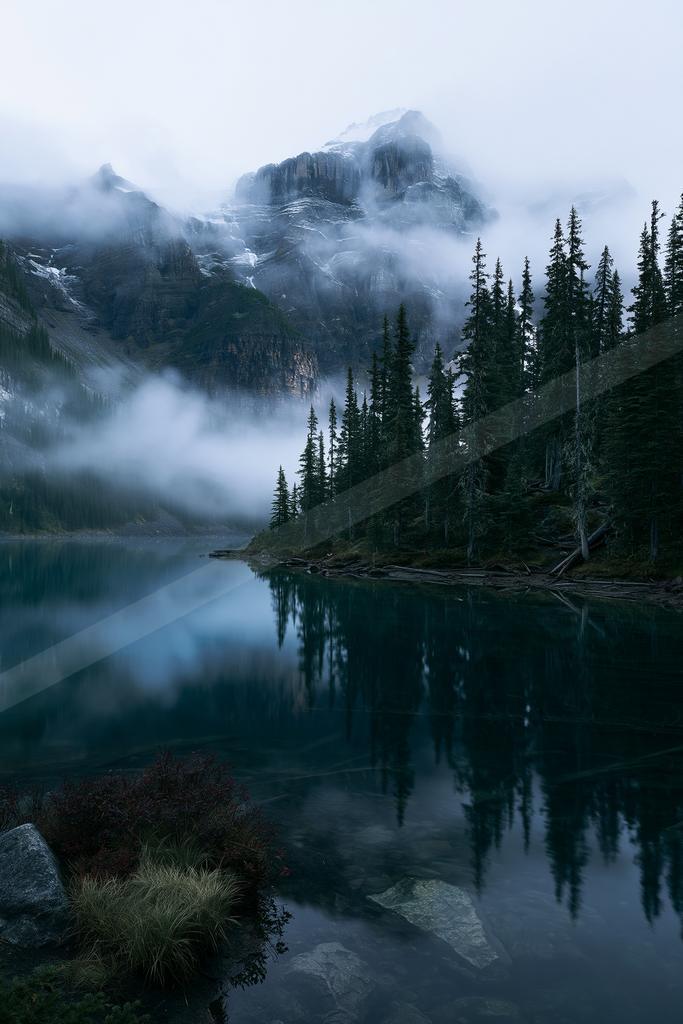 A serene water scene of lake, mountains, fog.