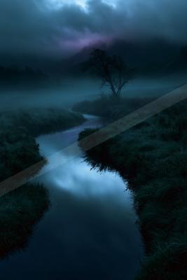 A calm river winds through dense fog and dark vegetation under a moody, cloudy sky at dusk, with a solitary tree visible on the bank.