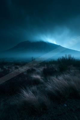 A blue hour landscape of mountains, desert, storm.