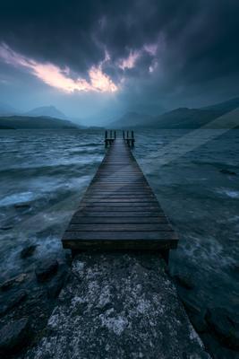 A blue hour long exposure sky scene of storm, ocean, lake.
