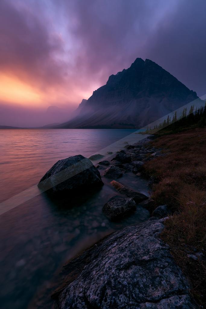 A blue hour long exposure water scene of lake, mountains, sunrise.