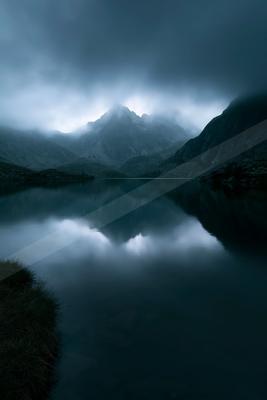 A black-toned moody photograph of lakeside, valley, alp.