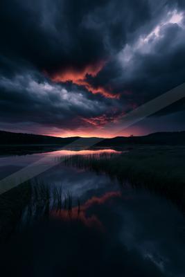 A serene water scene of lake, clouds, sunset.