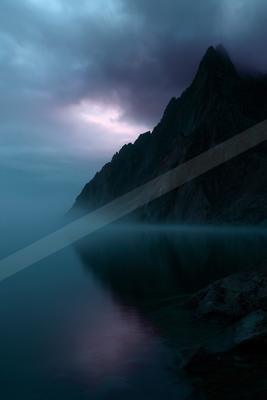 A blue hour water scene of lake, mountains.