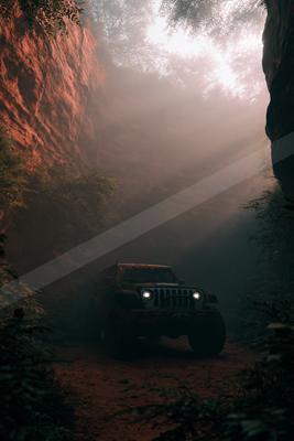 A black-toned moody photograph of jeep, cliff, valley.