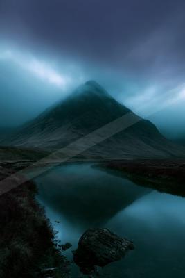 A blue hour long exposure water scene of lake, mountains, fog.