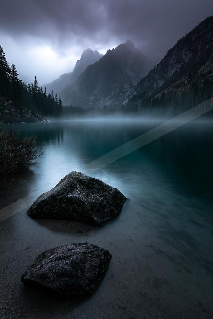 A black-toned moody photograph of lakeside, valley, seashore.