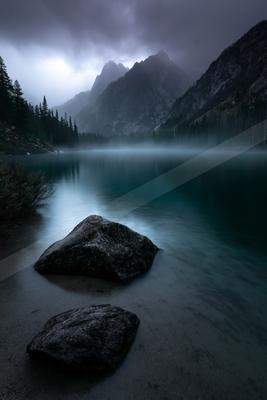 A black-toned moody photograph of lakeside, valley, seashore.