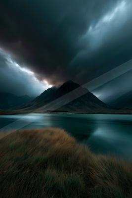A dramatic long exposure water scene of lake, storm, mountains.