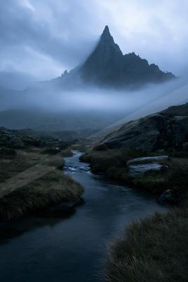 A dramatic landscape of mountains, fog.