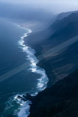 A moody aerial water scene of ocean, valley, beach.