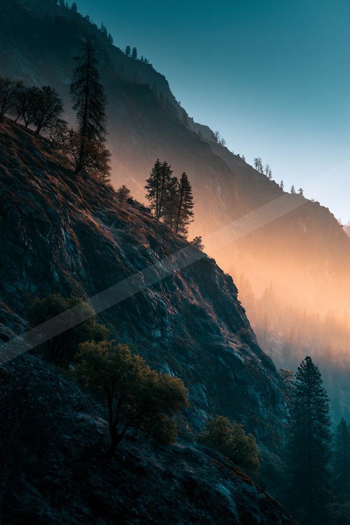 A blue hour long exposure landscape of mountains, trees, valley.