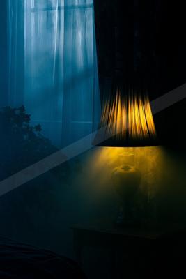 A black-toned moody photograph of lampshade, spotlight, table lamp.