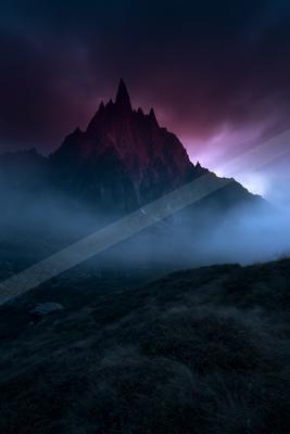 A dramatic landscape of mountains, fog.