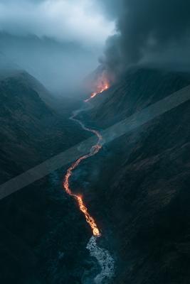 A glowing river of lava winds through a dark canyon, surrounded by rugged mountains under a stormy sky.