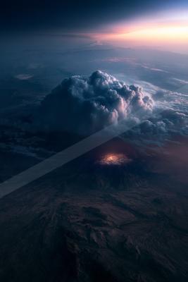 A black-toned moody photograph of volcano, wing, seashore.