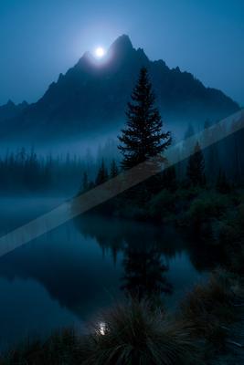 A bright moon illuminates a jagged mountain peak above a misty lake surrounded by dark pine trees, with the scene perfectly reflected in the calm water at night