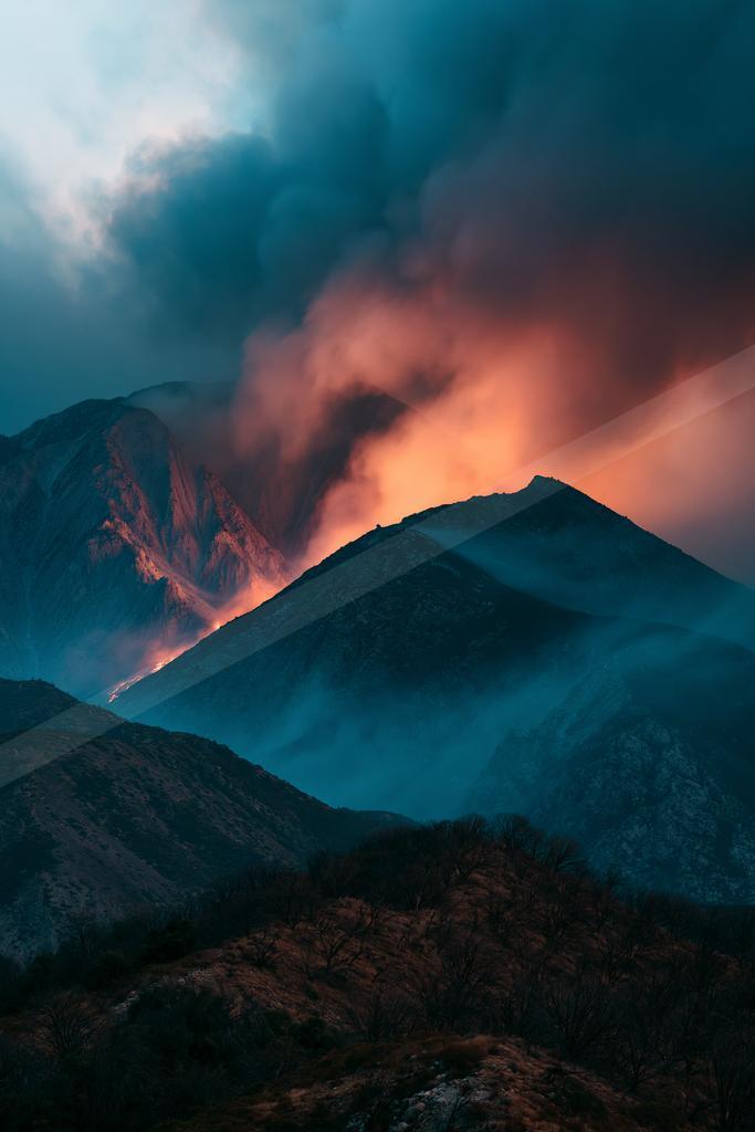 A dramatic landscape of mountains, fog.