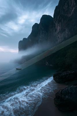 A serene coastal scene featuring a mist-shrouded shoreline, towering cliffs, and a small boat floating on calm waters.