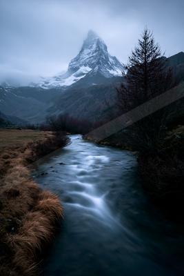 A moody landscape of mountains, river, valley.
