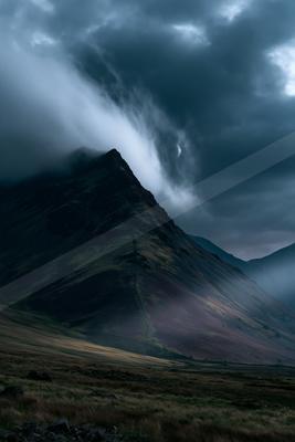 A dramatic landscape of mountains, storm, clouds.