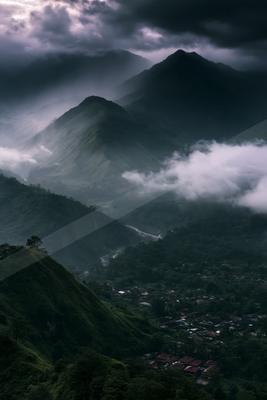 A dramatic landscape of mountains, valley, fog.