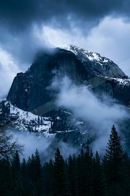 A dramatic landscape of mountains, fog.