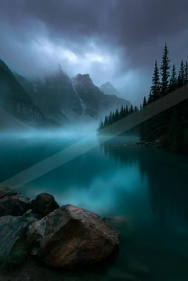 A blue hour long exposure water scene of lake, mountains, fog.