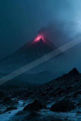 A dramatic nighttime view of a volcano erupting with bright red lava glowing at its peak, dark smoke billowing into the blue night sky, over a snowy rocky foreg