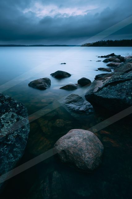 A blue hour long exposure water scene of a lake, rocks.