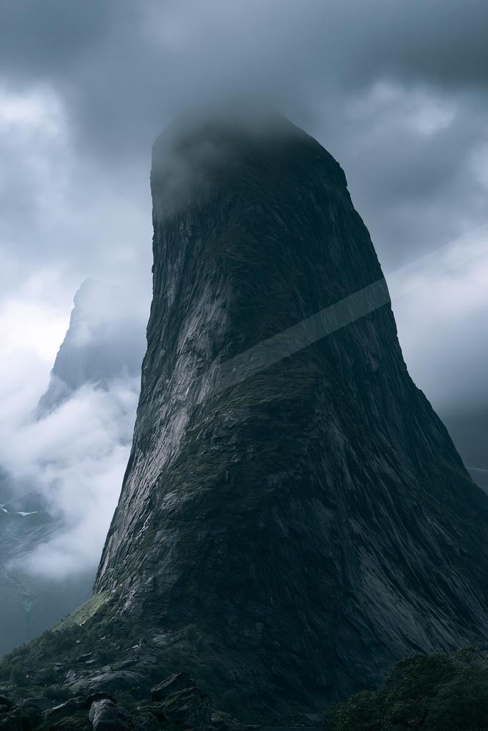 A dramatic landscape of mountains, fog.