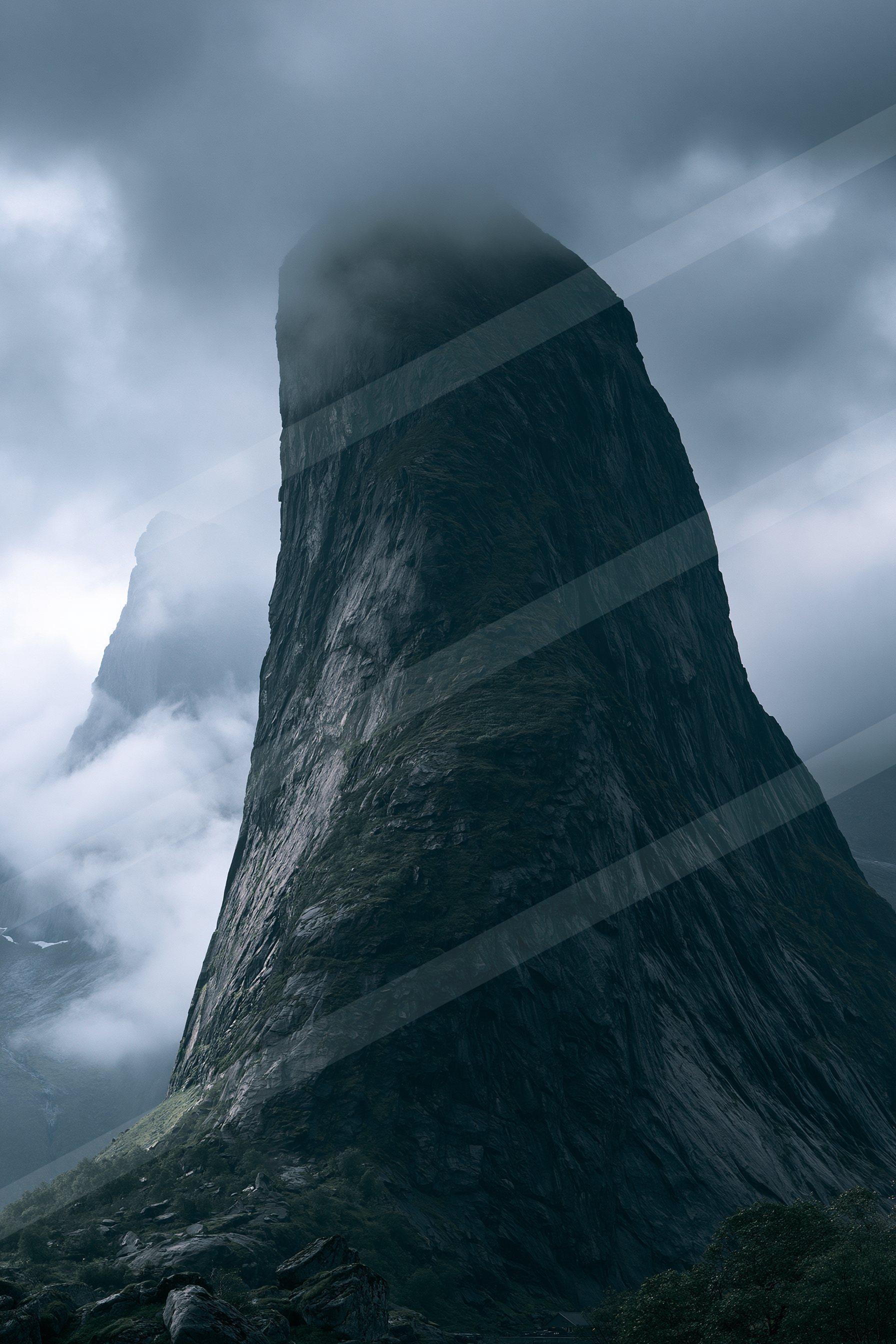 A towering mountain peak shrouded in misty clouds against a dark, moody sky.