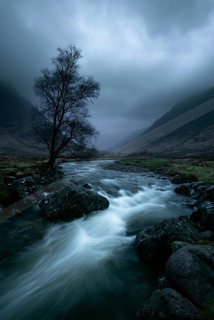 A moody water scene of river, waterfall, valley.