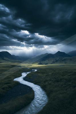 A dramatic long exposure water scene of river, storm, valley.