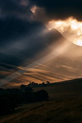 A dramatic landscape of mountains, storm, clouds.