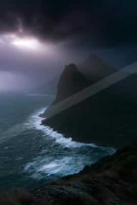 A black-toned moody photograph of promontory, seashore, cliff.