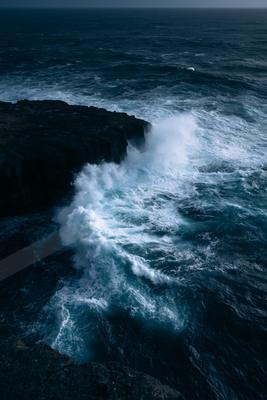A blue hour water scene of ocean, rocks.