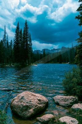 A blue hour water scene of lake, river, rocks.